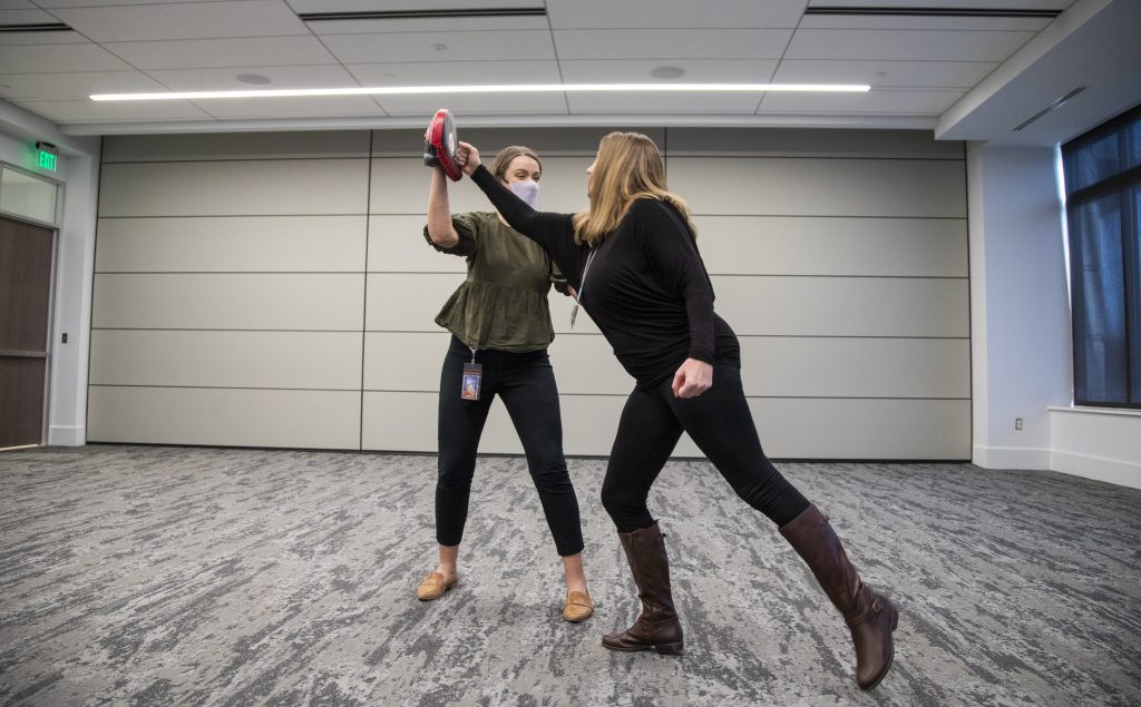 two women practicing self defense in a classroom