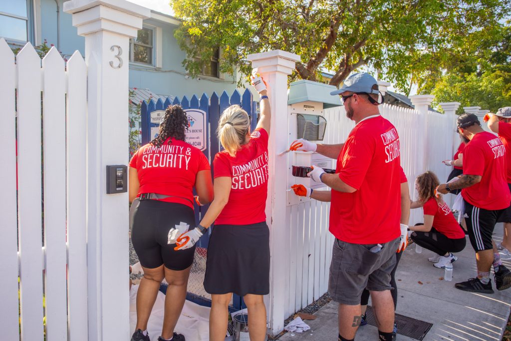 CPI Security employees volunteering by painting a fence together