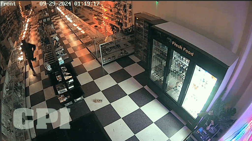 Security-camera view of a hooded person inside a business