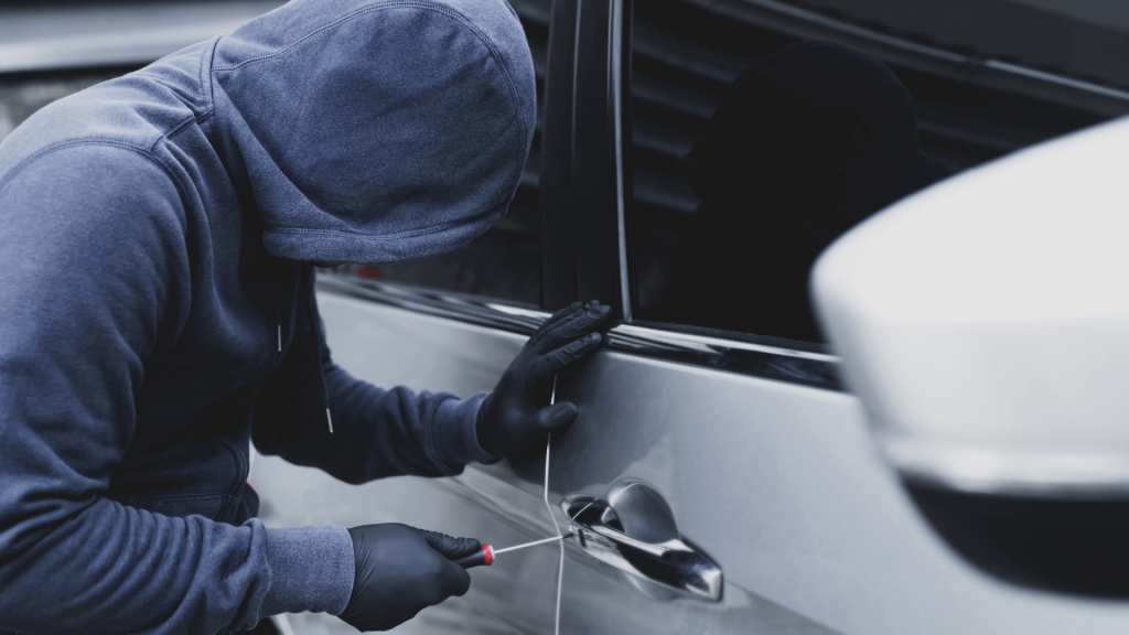 Hooded figure trying to break into car with screw driver