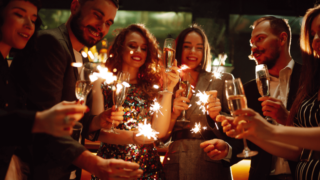 Group of people holding champagne glasses and sparklers
