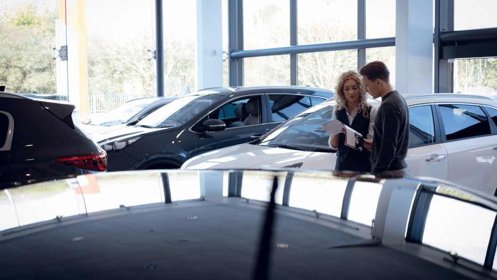 Car sales person showing pamphlet to customer inside of a Car dealership