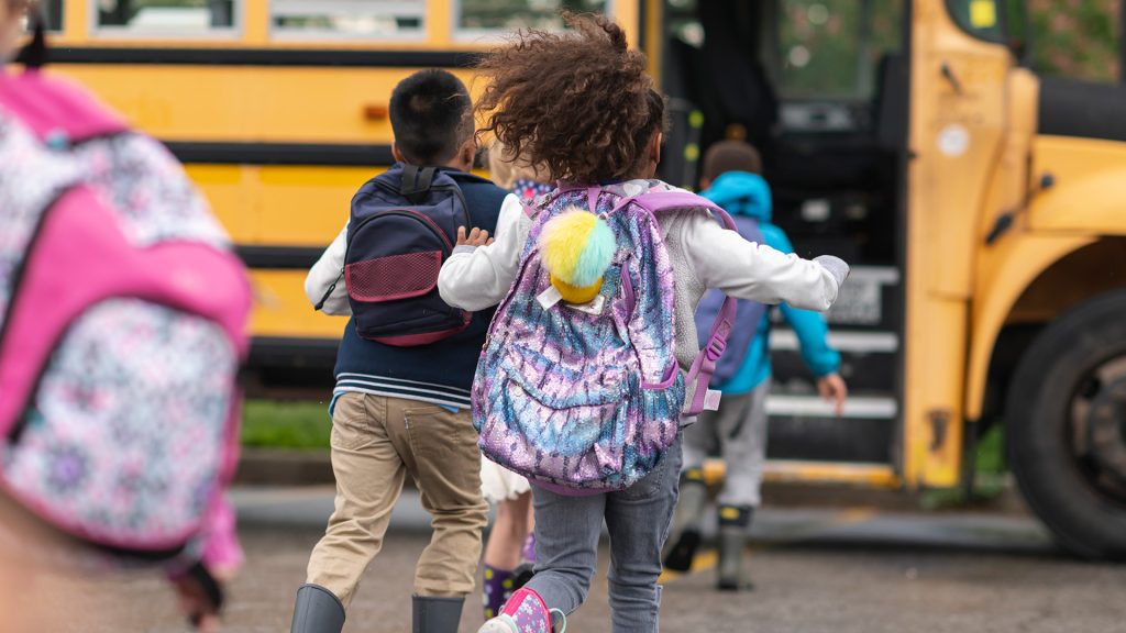 Kids running towards school bus