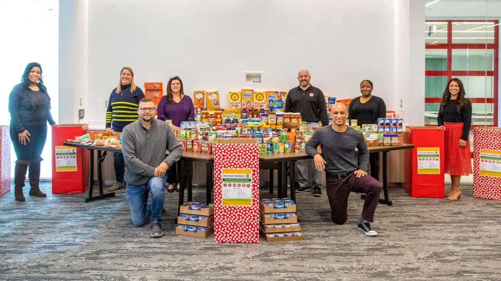 People posing with donated cans of food