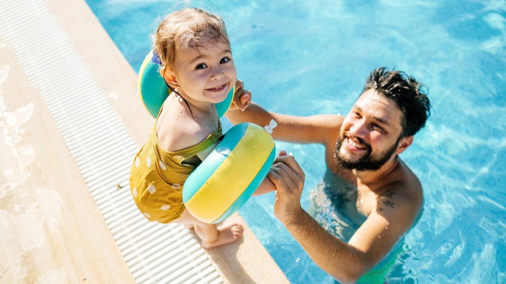 Father and child sitting in pool