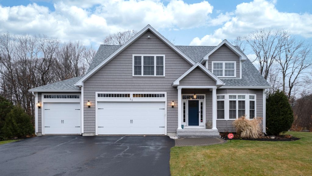 Gray-walled suburban house with white asphalt driveway House with CPI security sign in the front yard