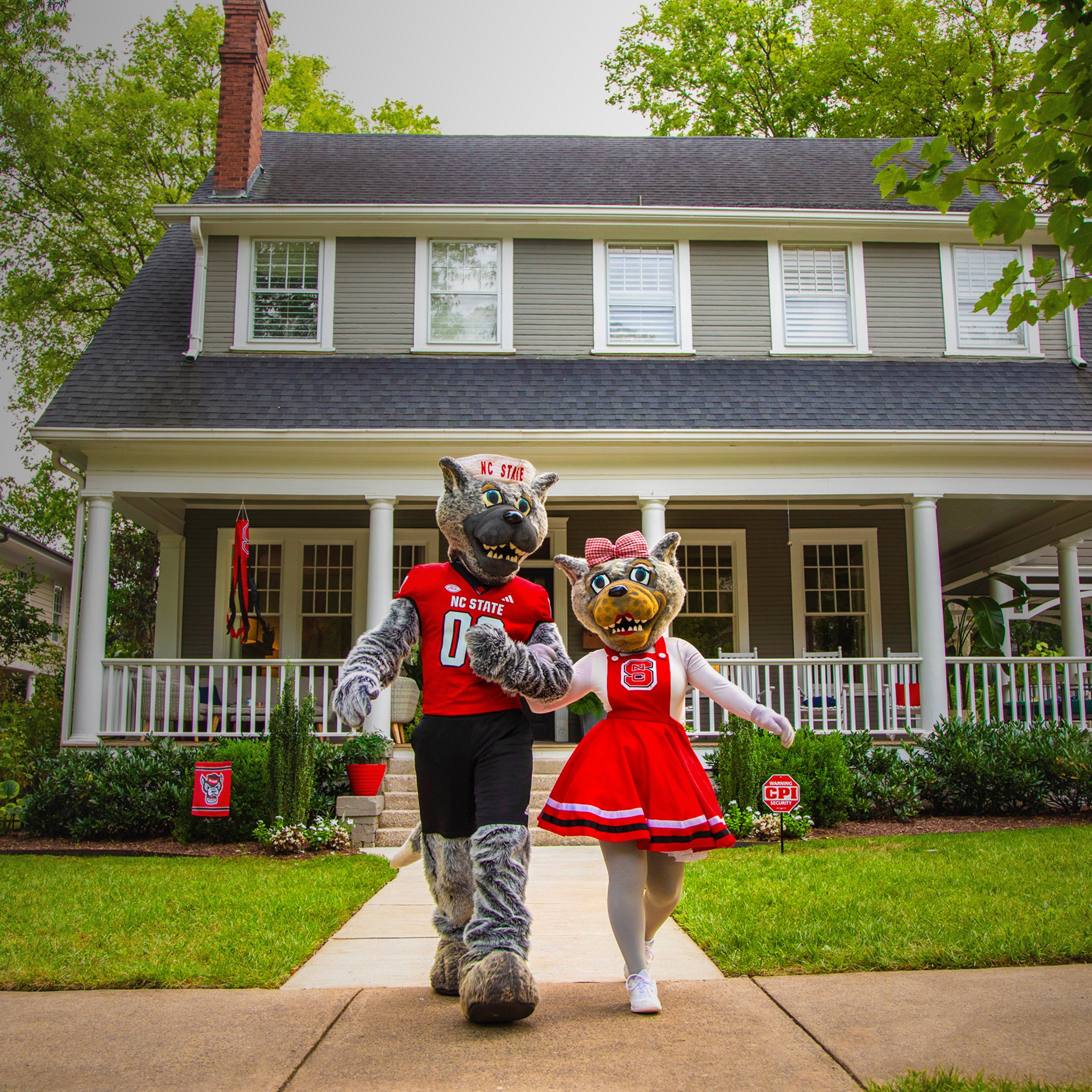 NC State mascots walking in front of a house