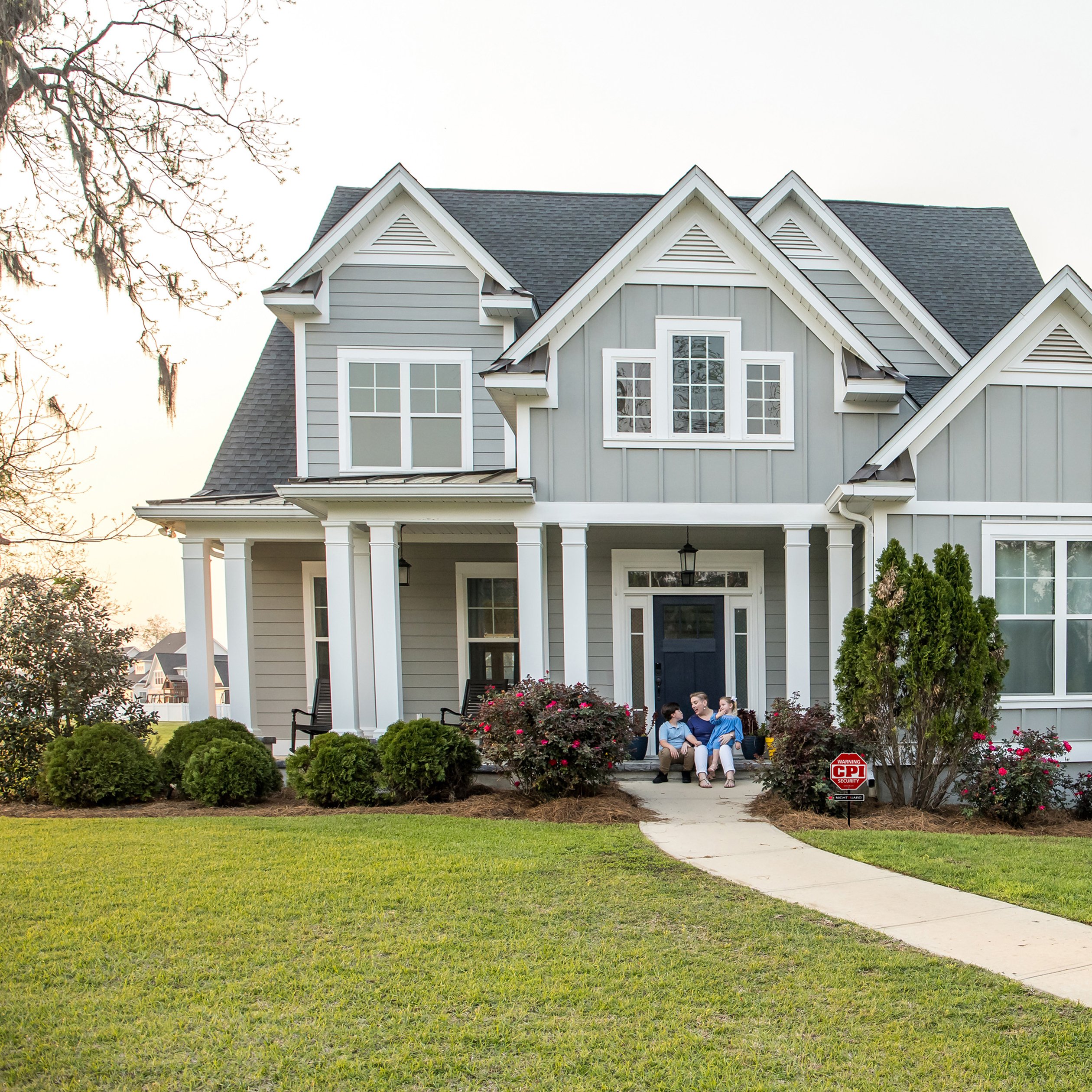 Large house with family sitting on front porch and CPI Security sign in the front yard