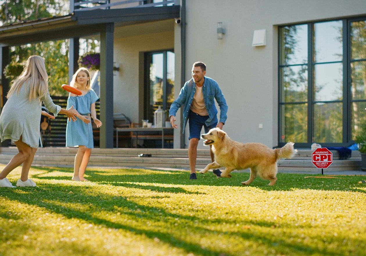 Family playing with dog outside next to CPI Security Yard Sign