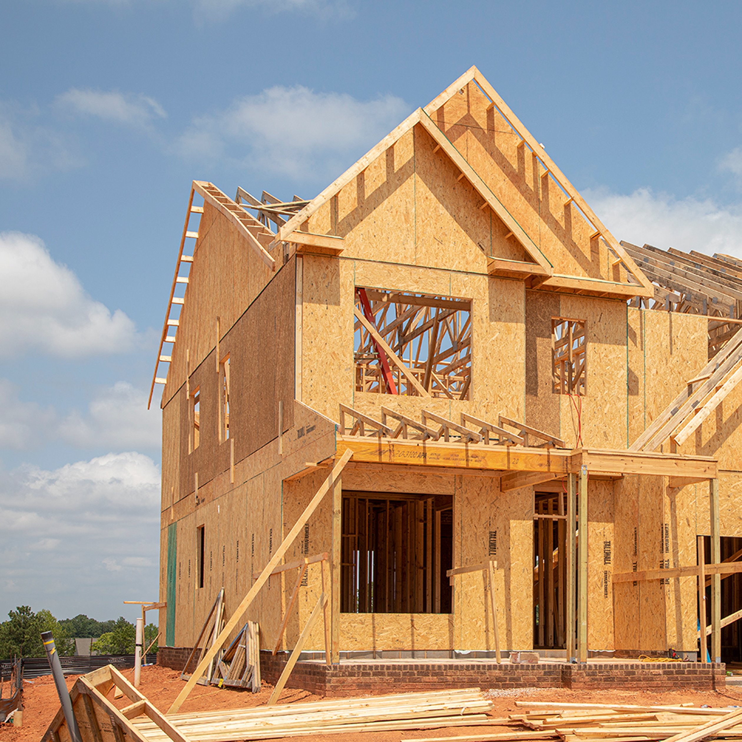 Large new home under construction with plywood exterior and exposed rafters