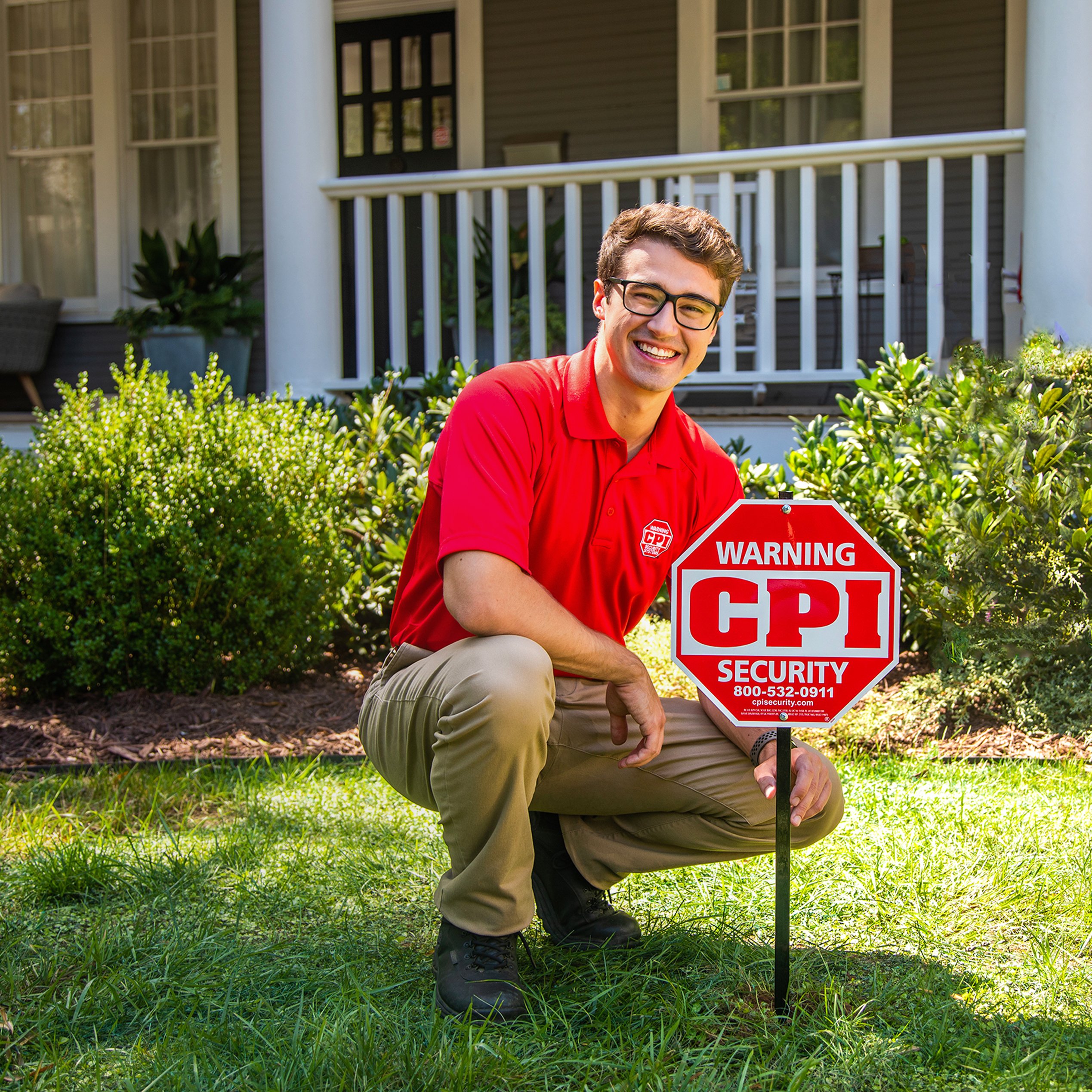 CPI technician posing by CPI Security yard sign