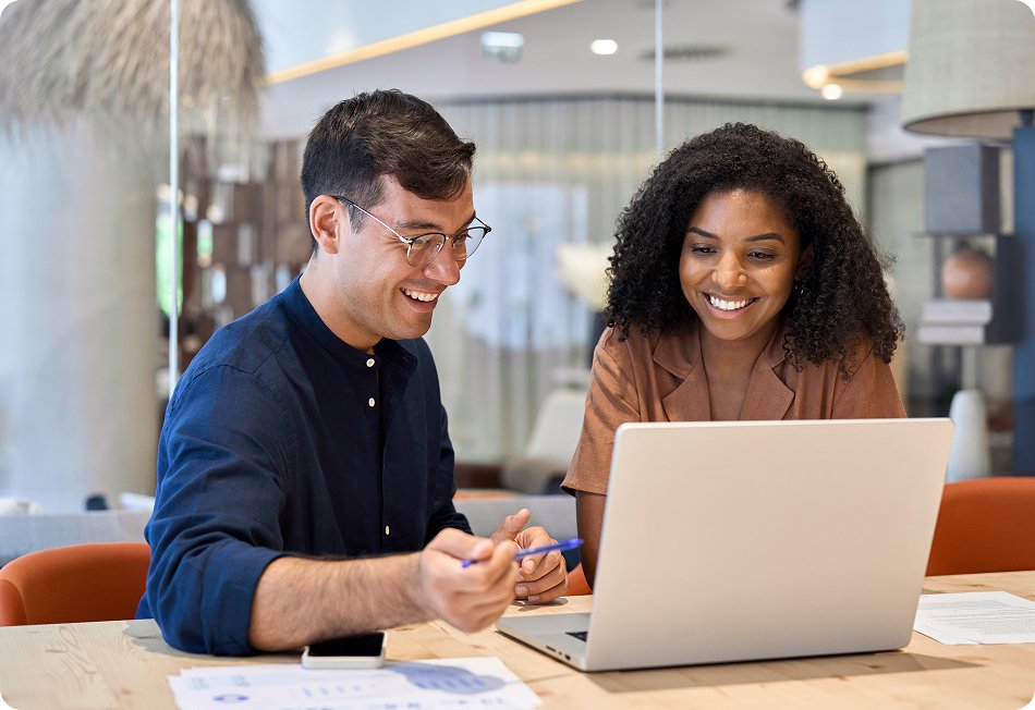 Two business professionals smiling while looking at laptop in office
