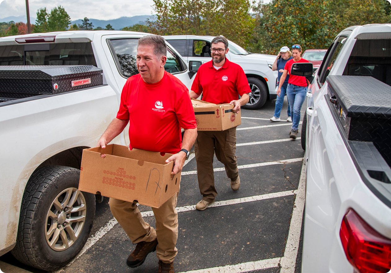 CPI employees carrying supplies in a parking lot in the Blue Ridge Mountains after flooding