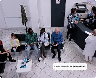 Overhead view of a busy office lobby with people sitting, standing at check-in, and talking, with overlaid text reading 'Crowd exceeds 10 person limit