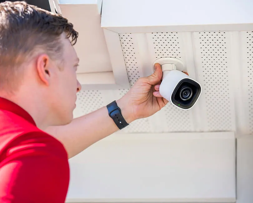 CPI Security technician installing outdoor camera on exterior of home