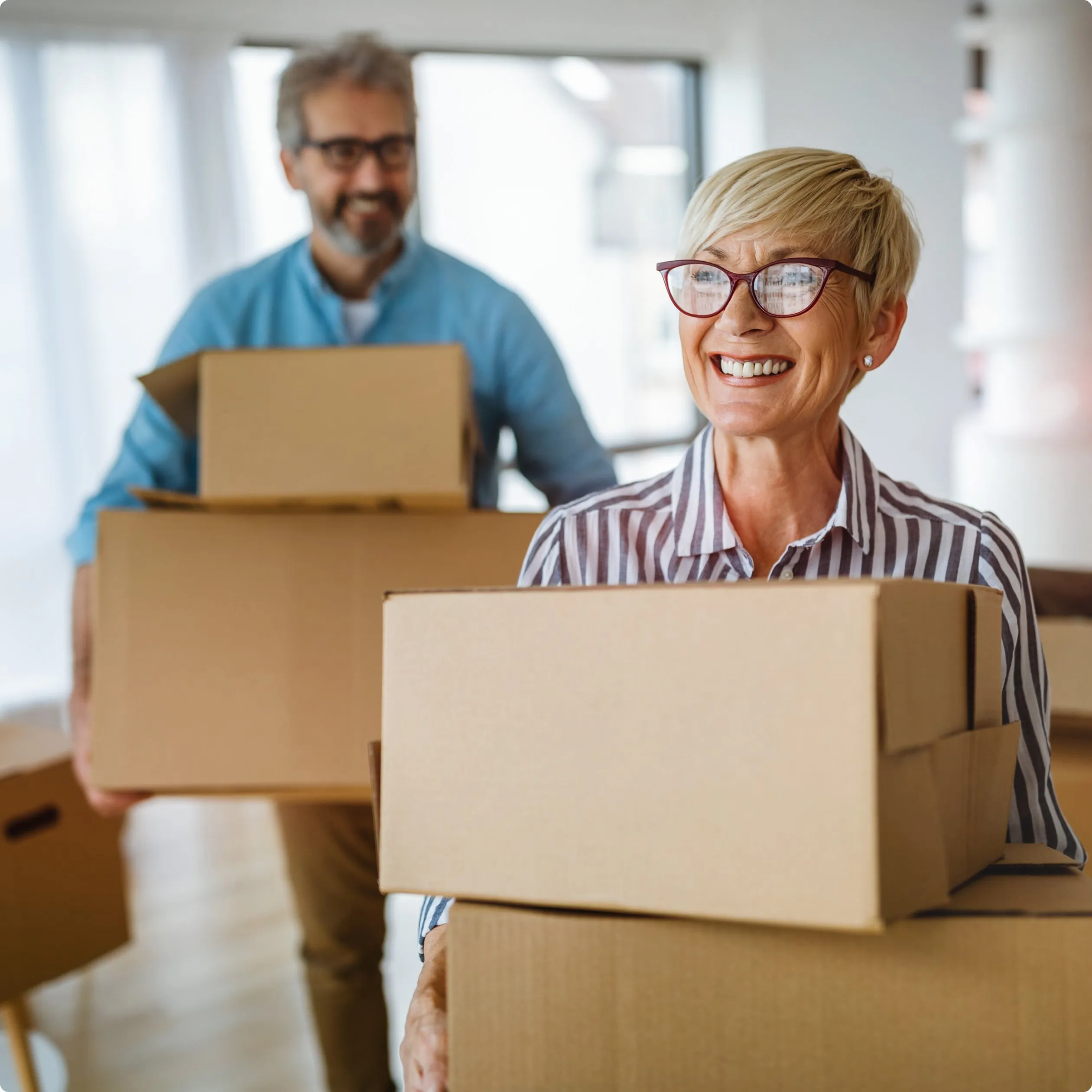 Man and woman, each carrying a box, smiling