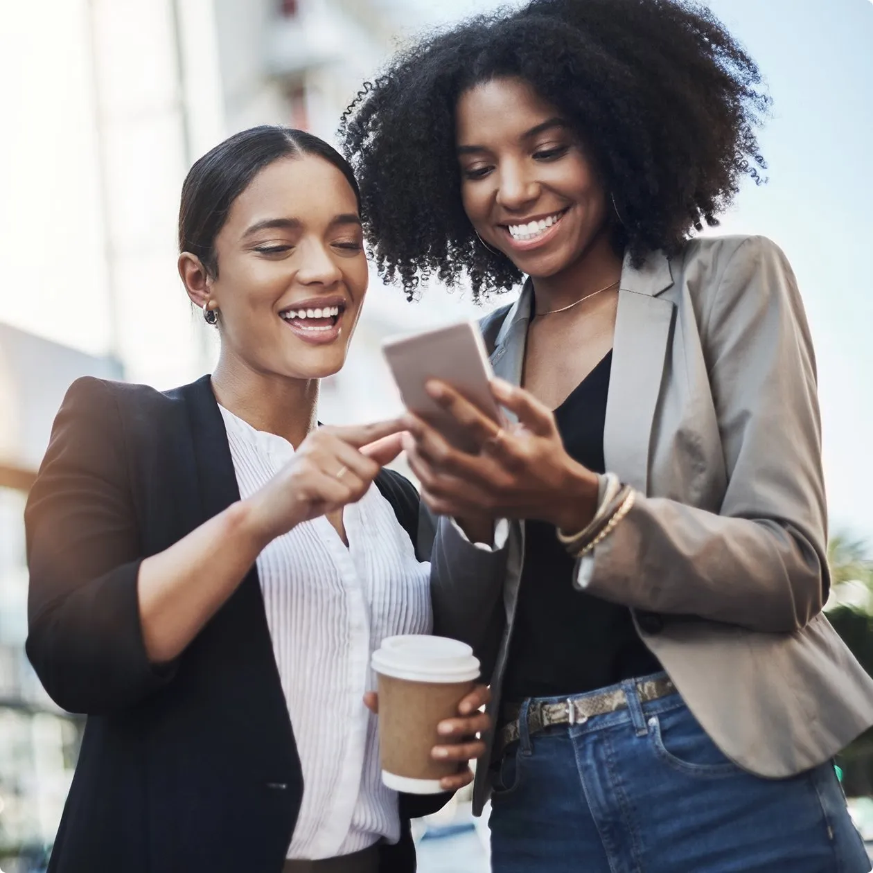 Two women smiling looking down at iPhone