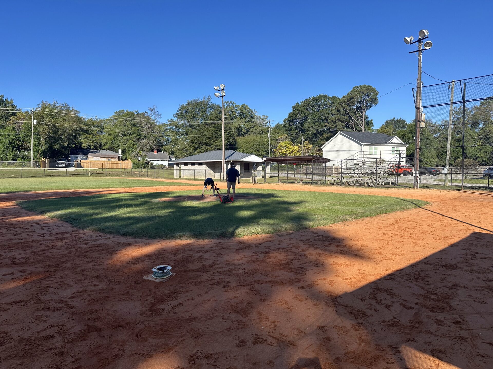 Two men standing on a rural baseball field