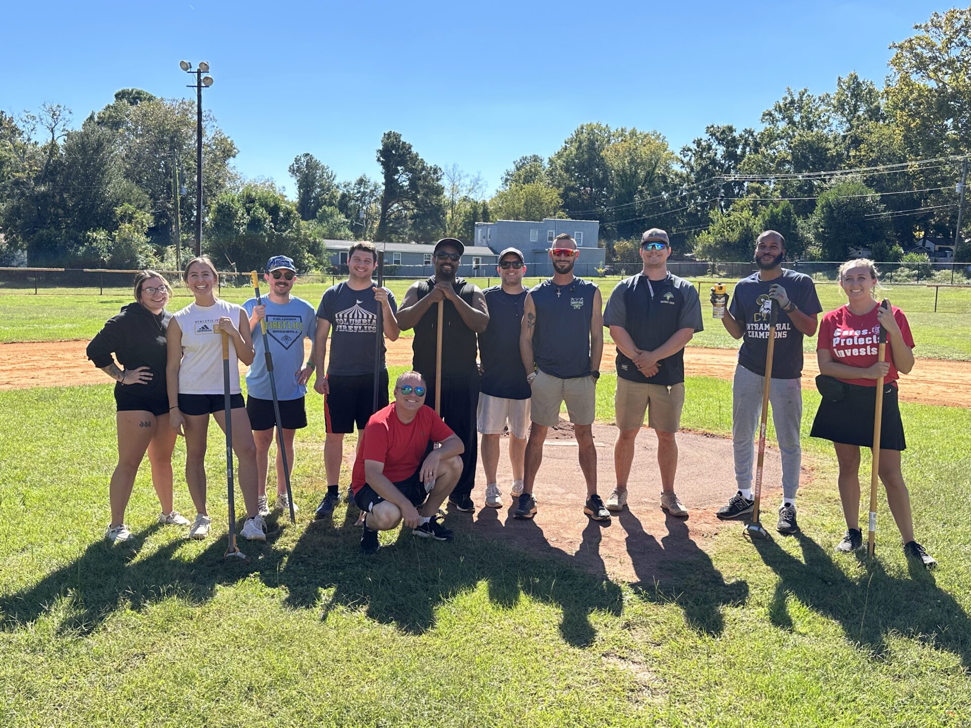 Group of people standing together for a photo while holding gardening tools