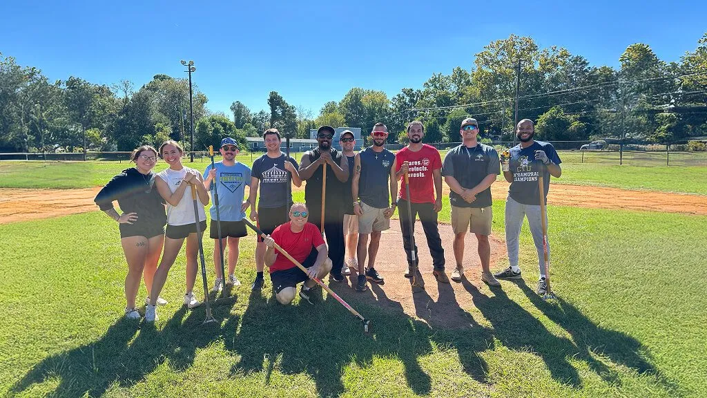 Group of people standing together for a photo while holding gardening tools