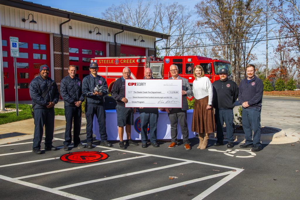 Fire department standing with CPI Security while holding a donated giant check