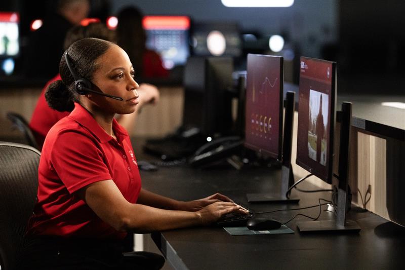 Woman at a security monitoring call center watching home surveillance feeds on computer monitor