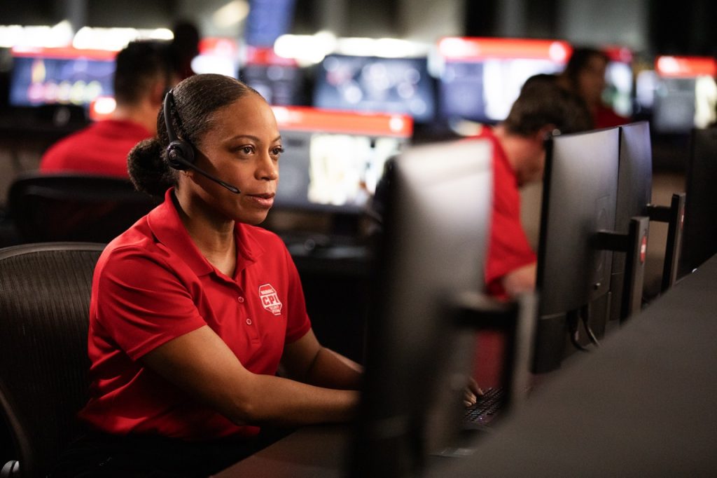 Woman at a security monitoring call center watching home surveillance feeds on computer monitor
